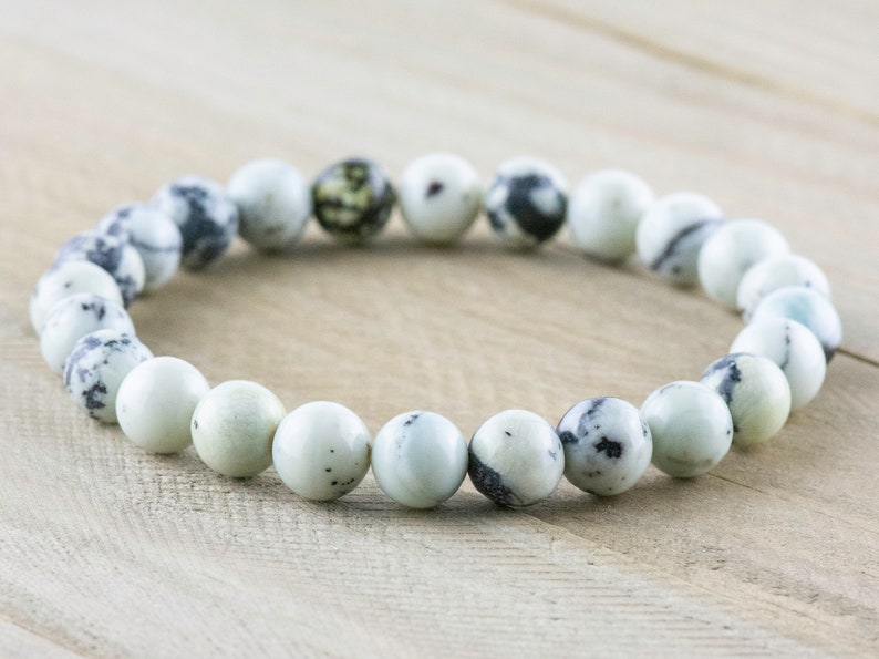 May include: A white and black speckled stone bracelet with round beads.