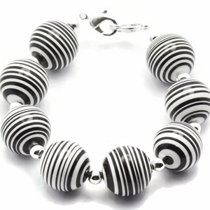 K&ouml;nnte beinhalten: Ein Armband aus schwarzen und wei&szlig;en Perlen mit einem silbernen Verschluss.
