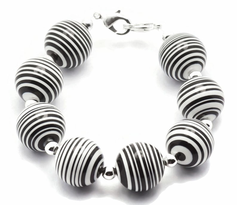 K&ouml;nnte beinhalten: Ein Armband aus schwarzen und wei&szlig;en Perlen mit einem silbernen Verschluss.