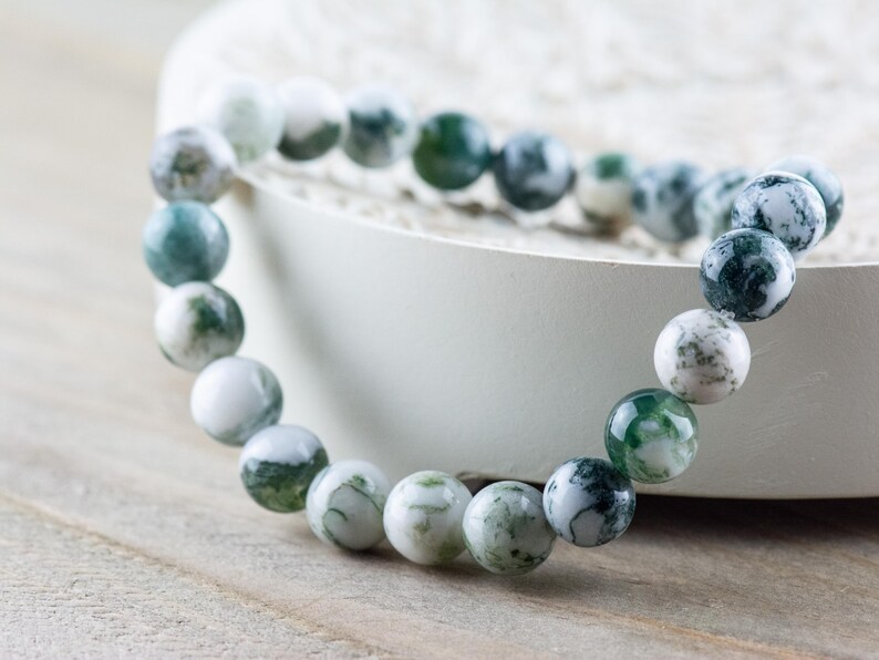 May include: A green and white agate beaded bracelet. The beads are round and have a natural, marbled pattern.