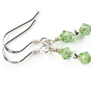 May include: A pair of silver dangle earrings with green crystal beads.