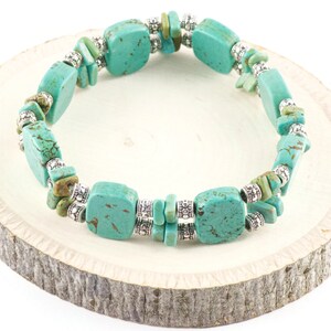 Op de afbeelding: Turquoise en zilveren armband met vierkante turquoise kralen en zilveren tussenkralen. De armband ligt op een houten oppervlak.