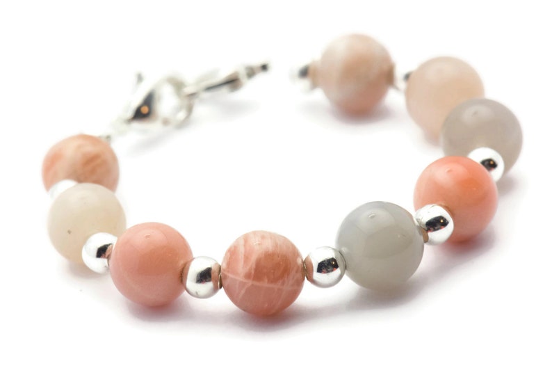 May include: A bracelet made of light pink, gray, and white sunstone beads with silver accents.
