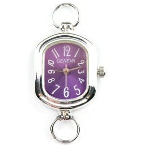 May include: Silver-toned Geneva watch with a rectangular purple face. The watch features white numerals and hands, with a small crown on the side. Two silver rings are attached to the top and bottom of the watch.