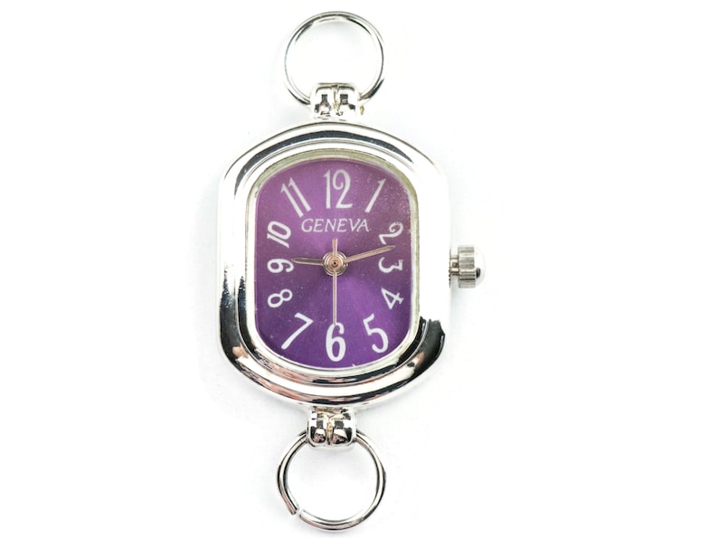 May include: Silver-toned Geneva watch with a rectangular purple face. The watch features white numerals and hands, with a small crown on the side. Two silver rings are attached to the top and bottom of the watch.