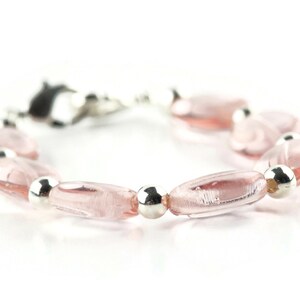 May include: A pink glass bead bracelet with silver beads. The bracelet has a clasp closure.