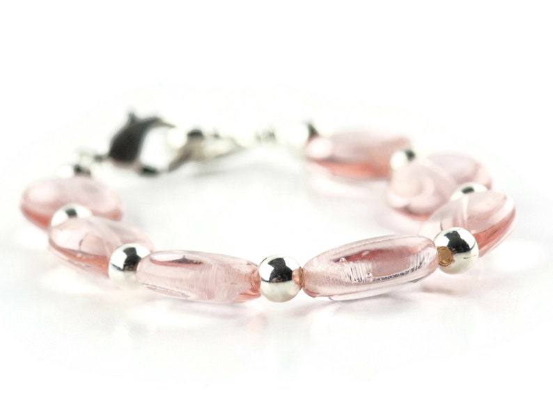 May include: A pink glass bead bracelet with silver beads. The bracelet has a clasp closure.