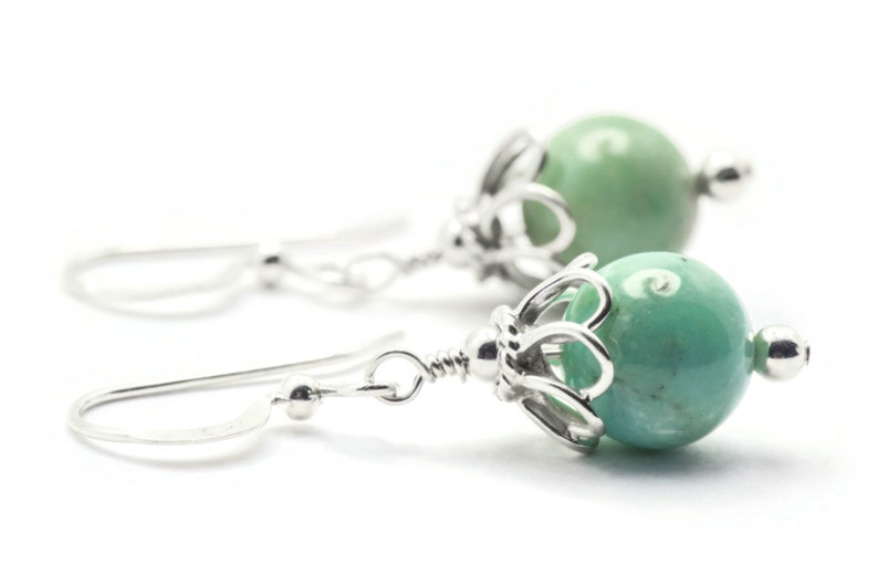 Puede incluir: Un par de pendientes de plata con cuentas de piedras preciosas verdes. Las cuentas est&aacute;n engastadas en un dise&ntilde;o de filigrana de plata.