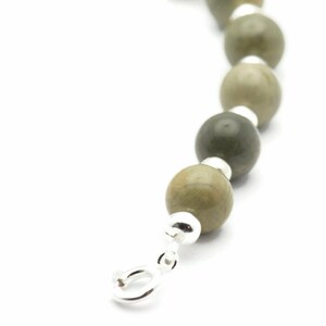 K&ouml;nnte beinhalten: Ein Armband aus Silber und gr&uuml;nen Steinen mit einem silbernen Verschluss.