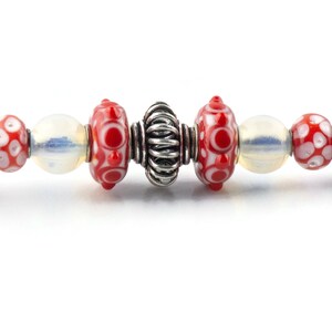 Peut inclure: Un bracelet &agrave; breloques en argent avec des perles de verre rouges et blanches et une perle d'espacement en argent.