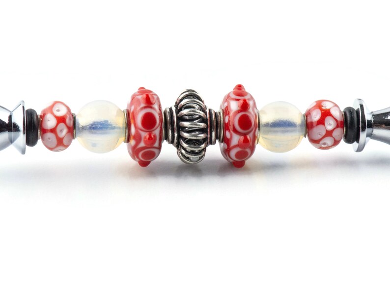 Peut inclure: Un bracelet &agrave; breloques en argent avec des perles de verre rouges et blanches et une perle d'espacement en argent.