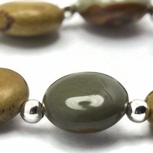 May include: A bracelet made with oval-shaped green and brown stones separated by silver beads.