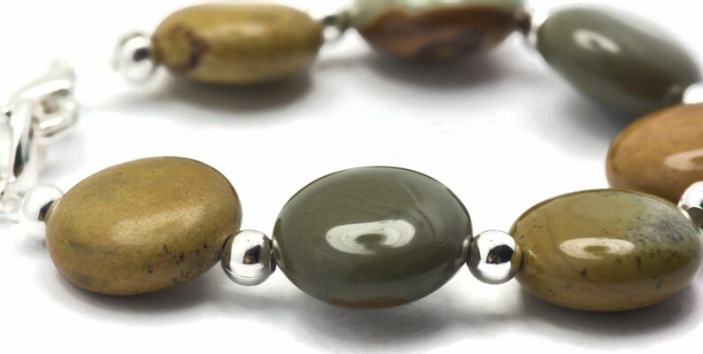 May include: A bracelet made with oval-shaped green and brown stones separated by silver beads.