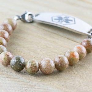 Pu&ograve; includere: Un braccialetto di perline rotonde multicolori nei toni del verde, marrone e arancione. Include una targhetta identificativa medica color argento con un simbolo medico e una chiusura.
