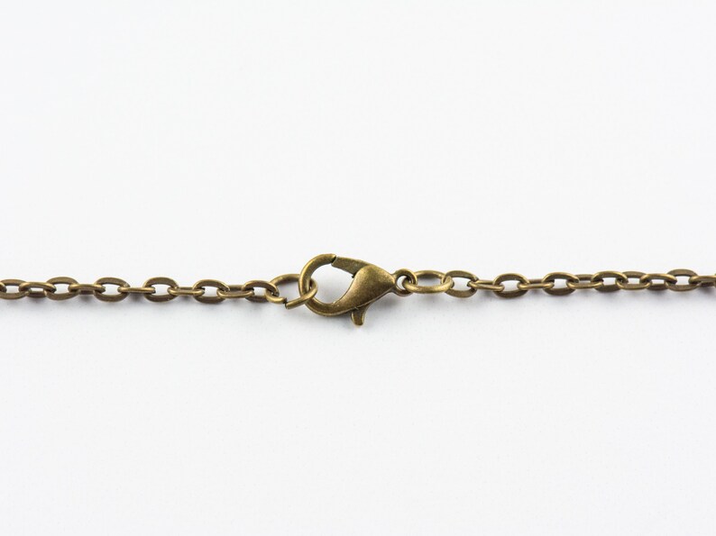 May include: A close-up of a gold-toned chain with a lobster clasp.