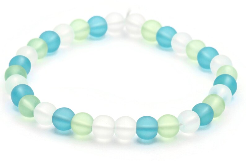 May include: A bracelet made of frosted glass beads in shades of white, light blue, and light green.