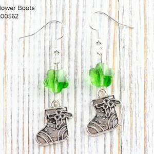 Pode incluir: Brincos pendurados com contas verdes em forma de flor e pingentes de bota prateados. Os brincos t&ecirc;m fecho de gancho. O texto "Green Flower Boots" e "EA00562" &eacute; vis&iacute;vel na imagem.