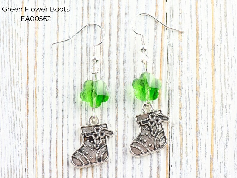 Pode incluir: Brincos pendurados com contas verdes em forma de flor e pingentes de bota prateados. Os brincos t&ecirc;m fecho de gancho. O texto "Green Flower Boots" e "EA00562" &eacute; vis&iacute;vel na imagem.