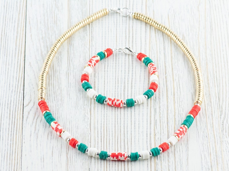 May include: A gold chain necklace and a bracelet with red, white, and green beads. The beads are arranged in a repeating pattern.