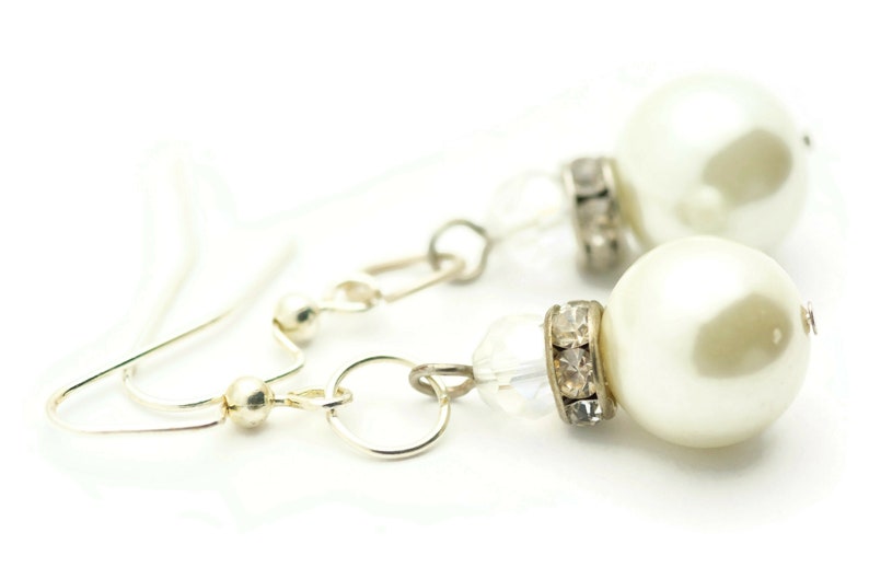 Peut inclure: Une paire de boucles d'oreilles en argent avec des accents de perles blanches et de cristal.