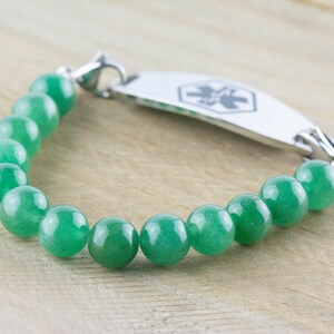 May include: A green jade beaded bracelet with a silver medical ID tag. The tag has a star of life symbol.
