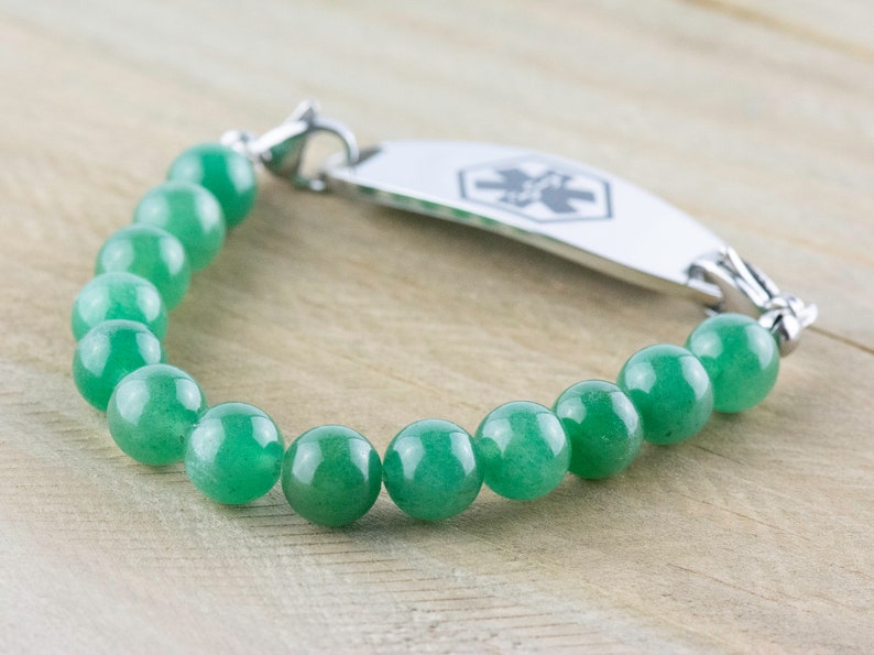 May include: A green jade beaded bracelet with a silver medical ID tag. The tag has a star of life symbol.