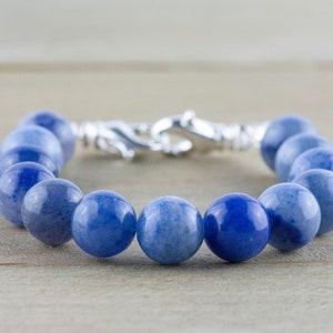 May include: A blue gemstone bracelet with a silver clasp. The bracelet is made of round beads and is approximately 18 cm in length.