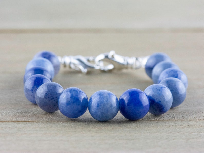 May include: A blue gemstone bracelet with a silver clasp. The bracelet is made of round beads and is approximately 18 cm in length.