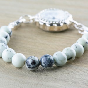 Peut inclure: Une montre argent&eacute;e avec un cadran blanc et un bracelet de perles en pierres blanches et noires.