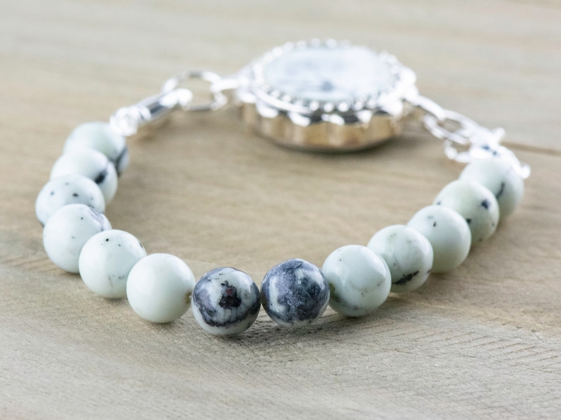 Peut inclure: Une montre argent&eacute;e avec un cadran blanc et un bracelet de perles en pierres blanches et noires.