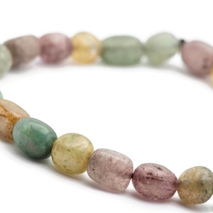 May include: A bracelet made of oval-shaped, multi-coloured gemstone beads. The beads are shades of green, brown, pink, and yellow.