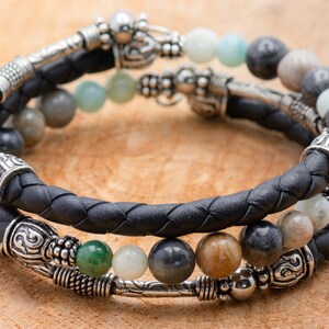 May include: A black leather bracelet with silver beads and green, brown, and gray stones.