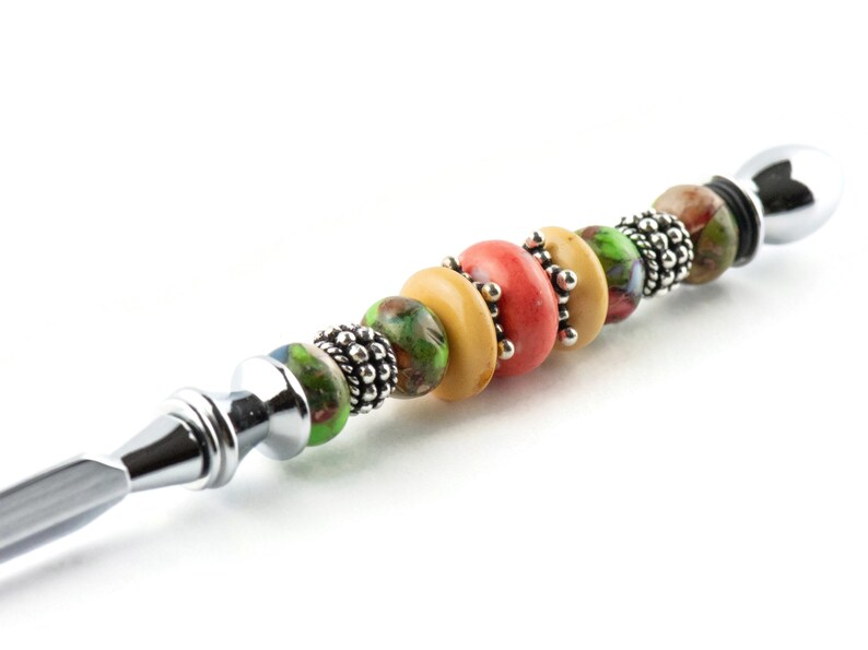 May include: A silver letter opener with a handle decorated with colourful glass beads. The beads are green, yellow and orange.