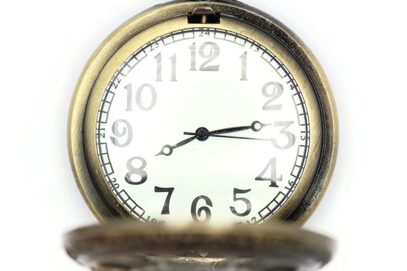 K&ouml;nnte beinhalten: Eine goldfarbene Taschenuhr mit wei&szlig;em Zifferblatt und schwarzen Zeigern. Das Zifferblatt der Uhr hat schwarze r&ouml;mische Ziffern f&uuml;r die Stunden und schwarze Markierungen f&uuml;r die Minuten.