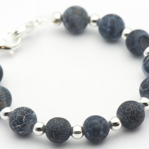 May include: A bracelet made of dark blue agate beads with silver spacers. The bracelet has a silver clasp.