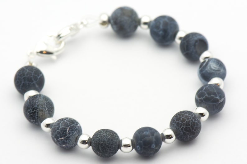May include: A bracelet made of dark blue agate beads with silver spacers. The bracelet has a silver clasp.