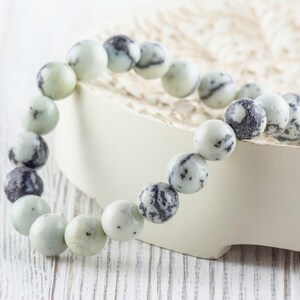 May include: A white and black speckled stone bracelet with round beads.