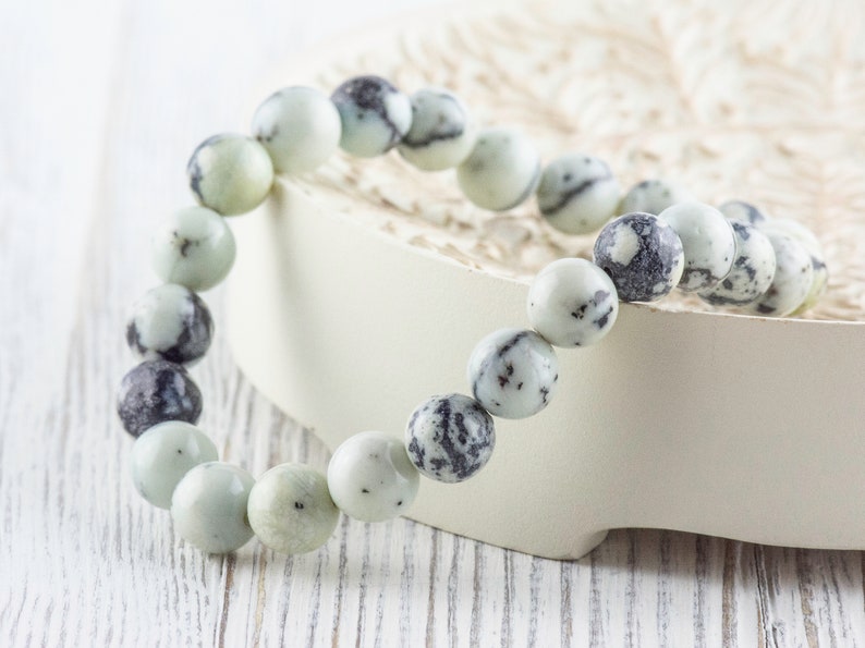 May include: A white and black speckled stone bracelet with round beads.