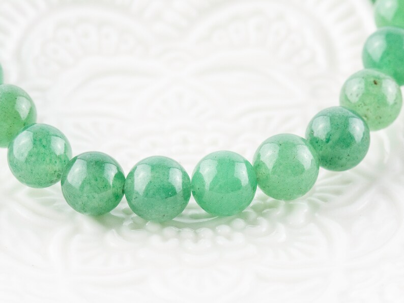May include: A green gemstone bracelet with round beads.