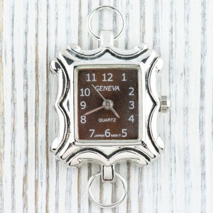 May include: A silver-toned watch with a square face and a brown dial. The watch face has black Roman numeral hour markers and the words "GENEVA" and "QUARTZ".