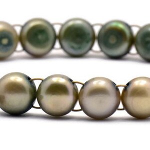 Op de afbeelding: Een armband gemaakt van groene en gouden parels met een vlinderbedel. De armband is gemaakt van draad en heeft een sluiting.