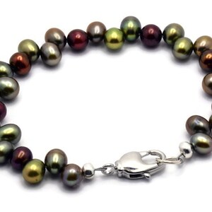 Puede incluir: Un brazalete de perlas multicolores con un cierre plateado. Las perlas son una mezcla de verde, marr&oacute;n y rojo.