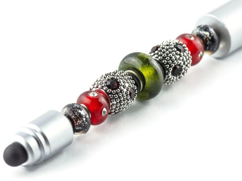 May include: A silver stylus pen with a black rubber tip and a series of colourful beads. The beads are red, green, and black with silver accents.