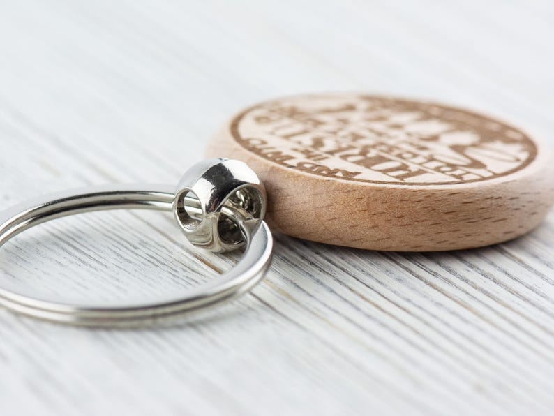 Op de afbeelding: Een houten sleutelhanger met een zilveren ring. Het hout is lichtbruin en de sleutelhanger heeft de tekst "I'm just here for the good times" gegraveerd.