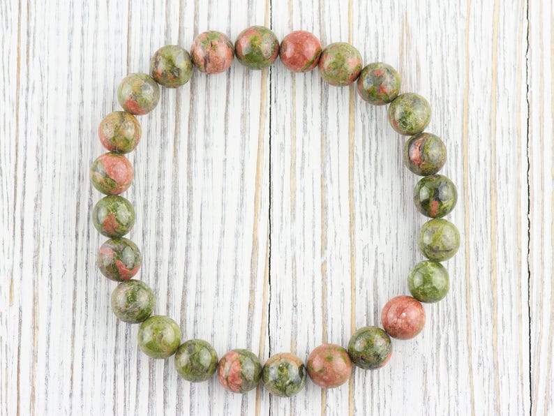 May include: A green, red, and brown speckled stone bracelet with round beads.