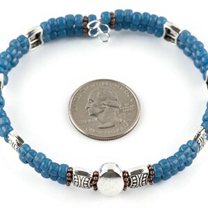 Button and Bows French Blue Cuff Memory Wire Bracelet on a white background. Quarter in center of bracelet is for a size reference.