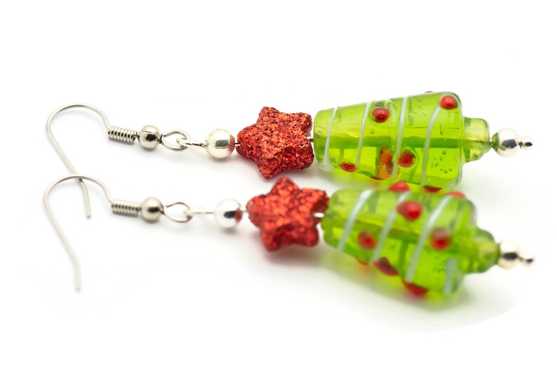 Op de afbeelding: Een paar groene glazen kerstboom oorbellen met rode glittersterren en zilveren haakjes.