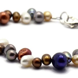 May include: A multi-colored freshwater pearl bracelet with a silver clasp. The pearls are various shades of white, cream, gray, brown, and blue.