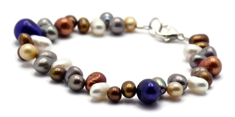 May include: A multi-colored freshwater pearl bracelet with a silver clasp. The pearls are various shades of white, cream, gray, brown, and blue.