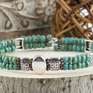 Button and Bows Desert Turquoise Cuff Memory Wire Bracelet close up on a wood piece with tree bark edging